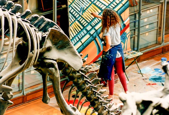Michelle Auboiron peint le dinosaure dans la grande Galerie de Paléontologie du Muséum d'hisoire Naturelle du Jardin des Plantes de Paris